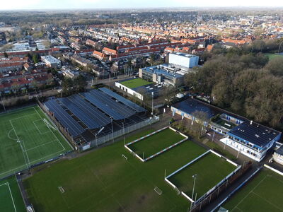 Luchtfoto van een sportcomplex met grasvelden en omliggende gebouwen in een stedelijke omgeving.